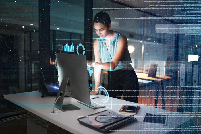 mujer trabajando en una computadora de pie revisando gráficos de datos