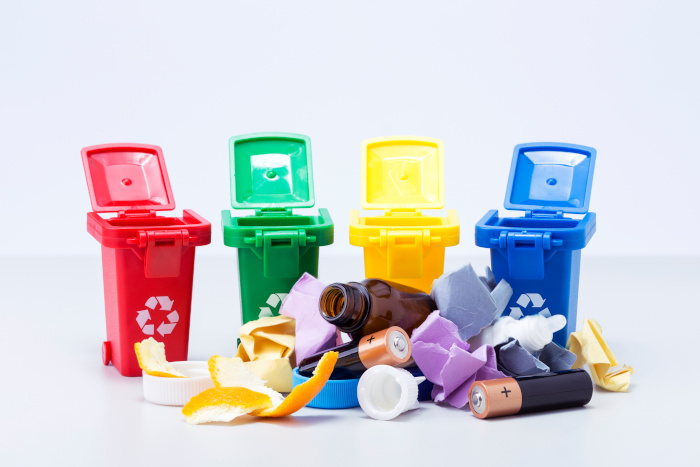 recipientes de colores para clasificar residuos, y residuos fuera de ellos en el suelo