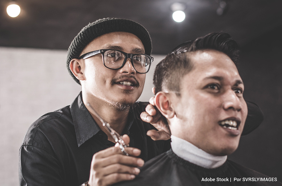 Cliente conversando sus vivencias a su peluquero mientras corta su cabello.