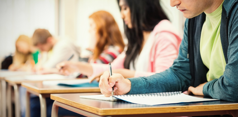 estudiantes hombres y mujeres sentados en pupitres de clases