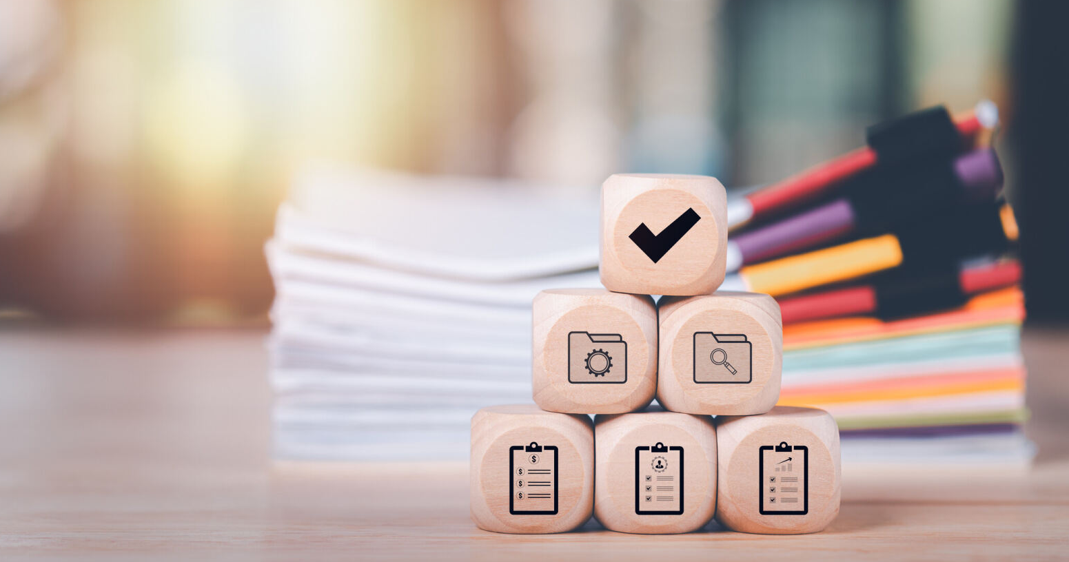 dados con dibujos de documentos, un check, una lupa, y detrás de los datos un grupo de expedientes en papel