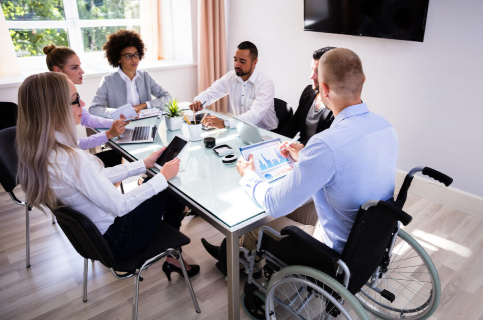 hombres y mujeres reunidos al rededor de una mesa, con trajes ejecutivos.